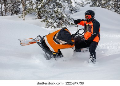 the guy makes a turn on a snowmobile, leaning on his left leg. on the background of the winter forest, leaving behind a trail of splashes of white snow. bright snowmobile and suit without brands. very - Shutterstock ID 1225249738