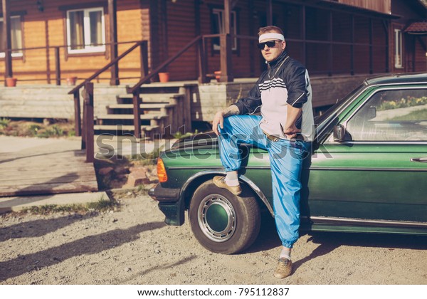 guy in the nineties\
stands near the car