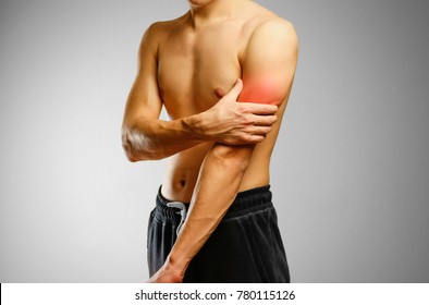 The Guy With No Shirt Holding Hand Of A Sick Bicep. The Pain In My Arm. Sore Biceps. The Pain Is Marked In Red.