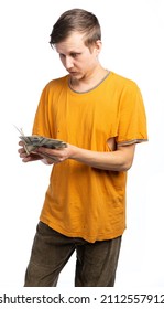 A Guy In Old Clothes, A Man In An Orange T-shirt, A Man Holding A Pile Of Money, Looks At Dollars In Surprise. Bankrupt, Fired Employee, Person. Isolated White Background