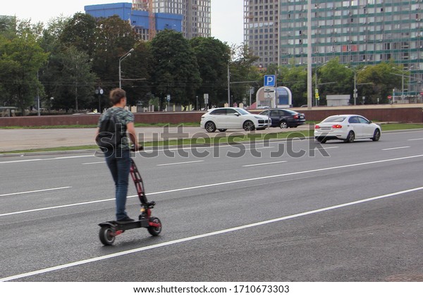 A guy on an electric scooter fast\
rides on a highway in the city, urban road safety\
kids
