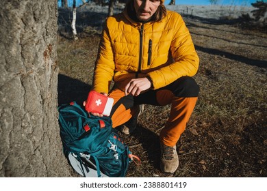 A guy on a hike shows a soy set of medicines, a demonstration of a small first aid kit, equipment for traveling in the mountains. High quality photo