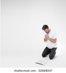 the guy is on his knees and prays to God and read?ng Bible