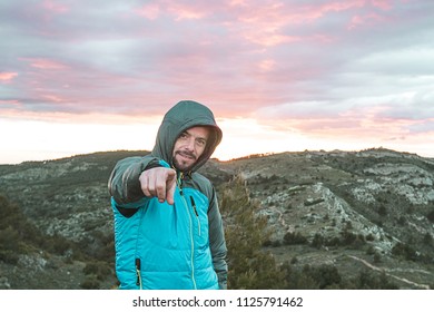 Guy on the mountain pointing at the camera. Mountaineer making a positive gesture