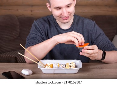 The Guy Opens A Package Of Soy Sauce For Sushi Rolls. The Concept Of Home Delivery Of Food