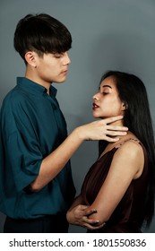 Guy In Oversize Dark Blue Shirt Strangulate His Girlfriend's Neck In Front Of Grey Limbo.