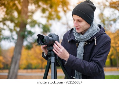 A guy in the park sets up the camera on a tripod.