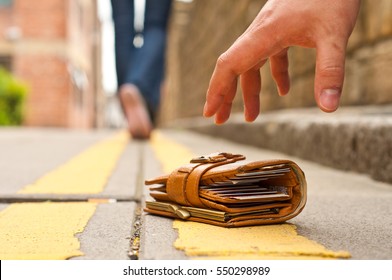 guy picking up a lost a lost purse/wallet