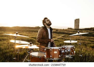 A Guy Playing Drums In The Middle Of A Green Meadow On A Sunny Day