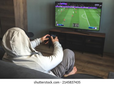 Guy Playing A Video Game Console. Game Is Football. Back View. Selective Focus