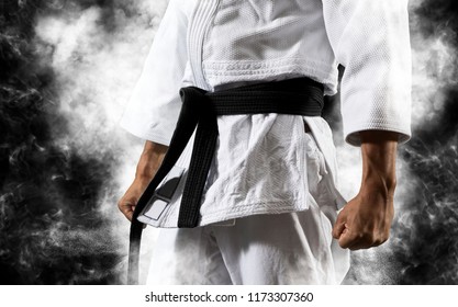 Guy poses in white kimono with black belt.  Japanese judo and sports concept
