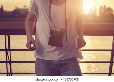 Guy posing outdoors with old camera.

