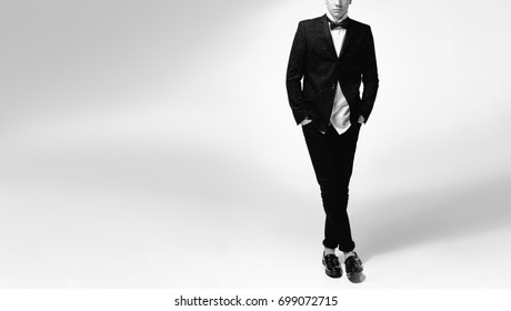 Guy posing in studio in black tuxedo