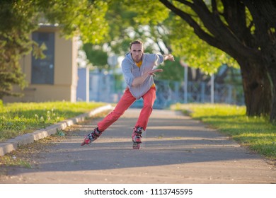 The Guy Quickly Rides On Roller Skates On A Long Road. Sports Driving. With Arms Outstretched At High Speed