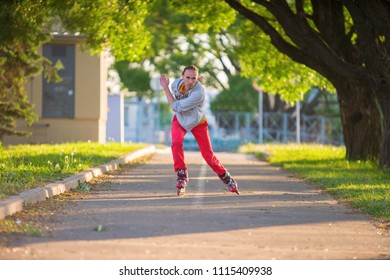 The Guy Quickly Rides On Roller Skates On A Long Road. Sports Driving. With Arms Outstretched At High Speed