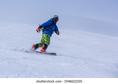 A Guy In A Red Jumpsuit Eating Freeride On A Snowboard On A Snowy Slope