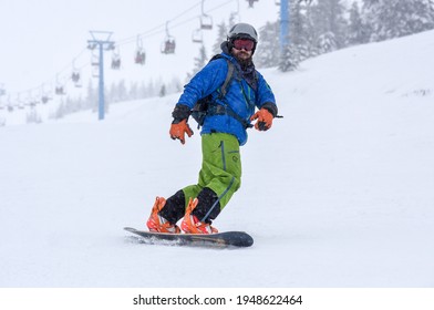 A Guy In A Red Jumpsuit Eating Freeride On A Snowboard On A Snowy Slope