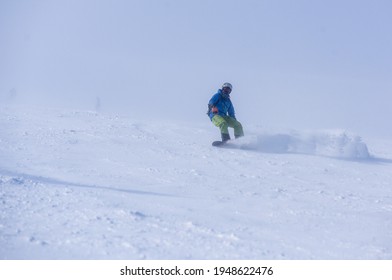 A Guy In A Red Jumpsuit Eating Freeride On A Snowboard On A Snowy Slope