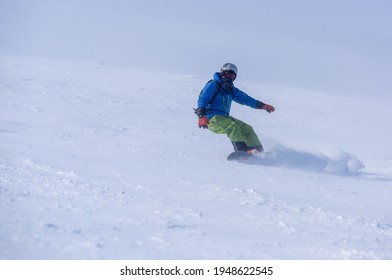 A Guy In A Red Jumpsuit Eating Freeride On A Snowboard On A Snowy Slope