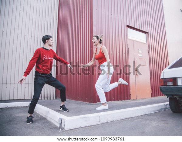 guy in red sweater and girl blonde in red shirt and\
white summer jeans