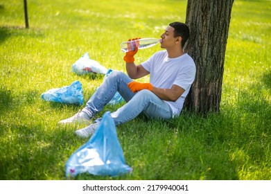 Guy resting under tree drinking water