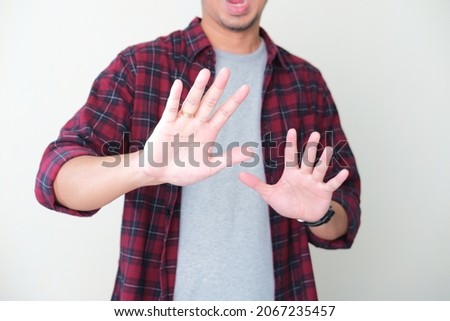 A guy screaming scared while his hands doing stop gesture