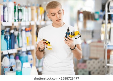 Guy selects various tools - screwdrivers, pliers for repairs in a supermarket