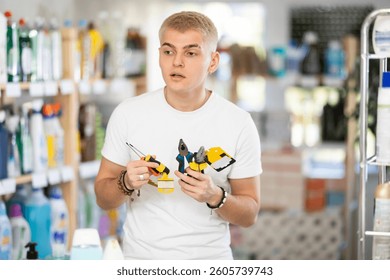 Guy selects various tools - screwdrivers, pliers for repairs in a supermarket
