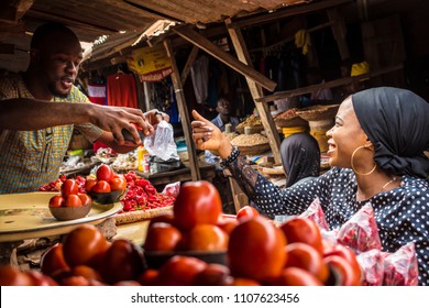 a guy selling tomatoes to a girl in a typical local african market