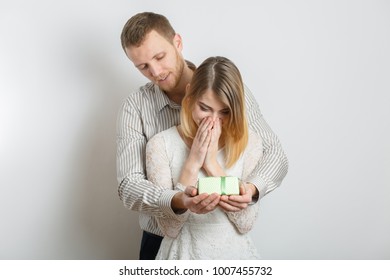 guy in a shirt gives a gift to girl, young couple, congratulates on a Valentine's Day, the concept of a holy Valentine, in a studio on a white background