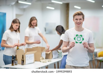 Guy Showing Eco Club Sign And Colleagues Behind