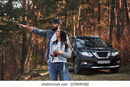 Guy Showing Something Beatiful. Enjoying The Nature. Couple Have Arrived To The Forest On Their Brand New Black Car.