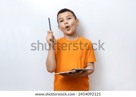 Guy shows expression of decision by raising pen up while holding notebook. Sincere children's emotions.