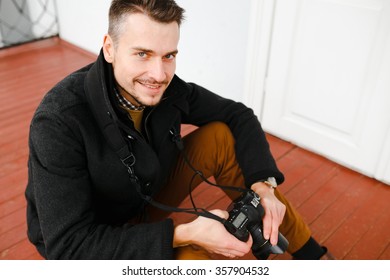 The guy sitting with a camera in hand, ulybaetsya, lively eyes, good looks, style