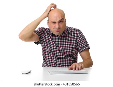 Guy Sitting At A Desk Working On A Computer, Scratching His Head. Isolated