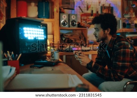 Guy sitting in front of tv monitor and playing video console in garage