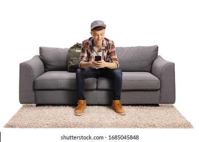 Guy sitting on a sofa and typing on a mobile phone isolated on white background
