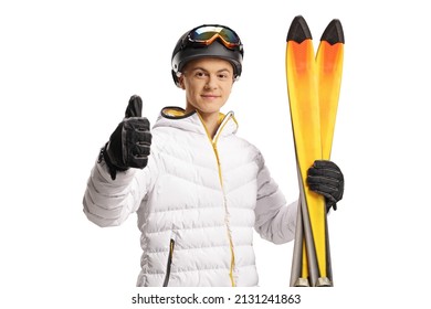 Guy with ski goggles and jacket holding a pair of skiis and gesturing thumbs up isolated on white background