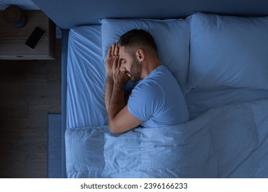Guy Sleeping Holding Hands Near Face Enjoying Rest Lying In Cozy Bed In Modern Bedroom Interior. European Middle Aged Guy Napping At Night. Recreation And Healthy Sleep Concept. Low Light, Top View - Powered by Shutterstock