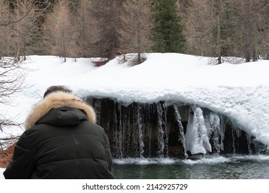 Guy Squatting At A Frozen Waterfall