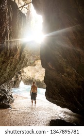 guy standing in the cave with a view of the waves of the ocean