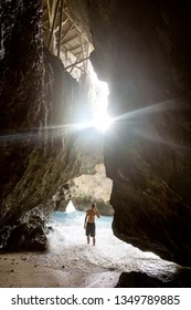 guy standing in the cave with a view of the waves of the ocean