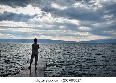 A guy standing and looking at the mesmerizing views of sea and sky