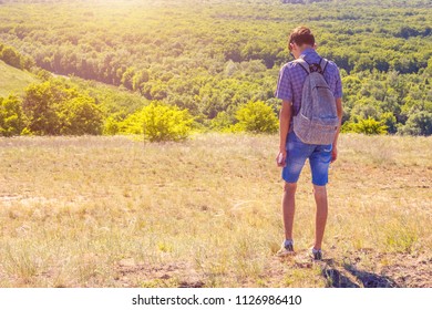 guy standing on a hill with backpack travel concept tinted