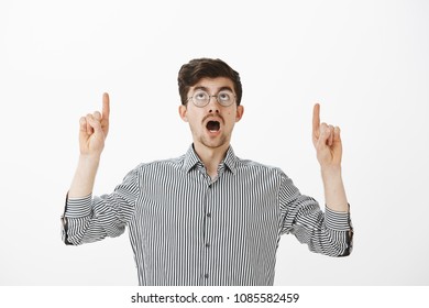 Guy Standing Still Worrying Ceiling Will Fall. Interested Creative Smart Man With Beard And Moustache, Pointing And Looking Up With Dropped Jaw, Seeing Something Curious Over Gray Background