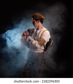 A Guy In A Steampunk Image, A Pilot Or A Mechanic. Retro Style, Fantastic Image. Portrait In Smoke. Repairs The Steam Engine