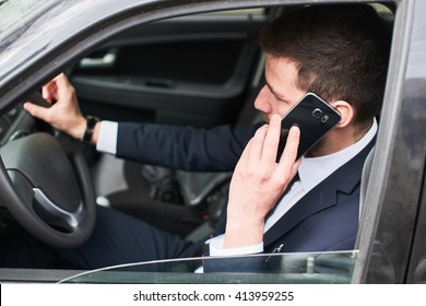 The Guy In The Suit Sitting Behind The Wheel Of A Car And Talking On A Cell Phone