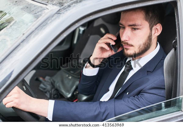 The guy in the suit sitting behind the wheel\
of a car and talking on a cell\
phone