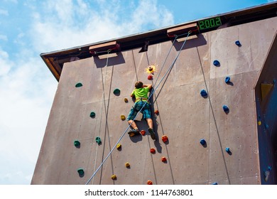 The Guy The Teenager Climbs To The Top Of The Artificial Rock, Is Engaged In Rock Climbing