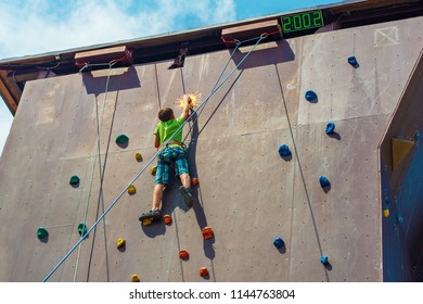 The Guy The Teenager Climbs To The Top Of The Artificial Rock, Is Engaged In Rock Climbing